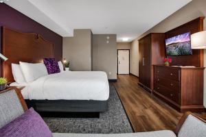 ein Hotelzimmer mit einem großen Bett und einem Flachbild-TV in der Unterkunft Ascent on Main in Parker