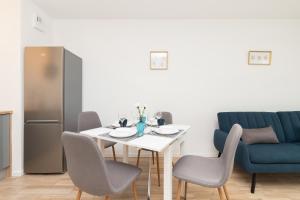 a dining room with a table and chairs and a refrigerator at Apartments Św. Brata Alberta by Renters in Gdańsk