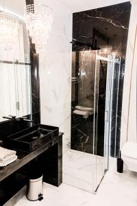 uma casa de banho em preto e branco com um chuveiro e um lavatório em Hypnotize Apartment Glamour em Konin