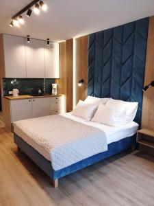 a bedroom with a large bed with a blue headboard at Albus 112 ApartPark in Świnoujście