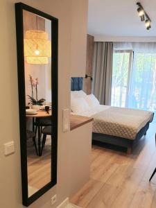 a bedroom with a bed and a table and a mirror at Albus 112 ApartPark in Świnoujście