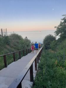 a group of people walking on a boardwalk near the ocean at Mini Hotel Уютный дворик in Odesa