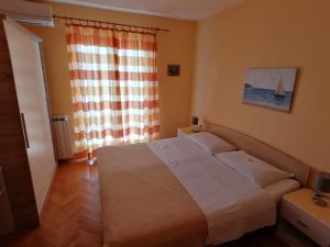 a bedroom with a bed and a window with a sailboat at Apartments Tonka in Mošćenička Draga