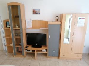 a room with a desk with a television and a cabinet at Apartments Tonka Franković in Mošćenička Draga