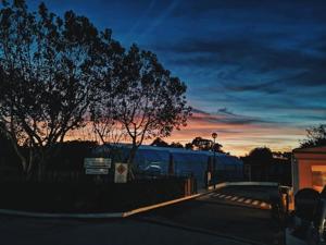 a train is parked next to a fence at sunset at Camping Villa Park Zambujeira do Mar in Zambujeira do Mar
