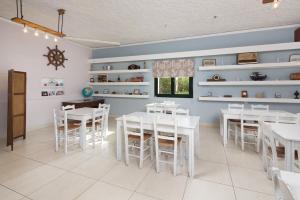 a dining room with white tables and white chairs at The Wave in Sidari