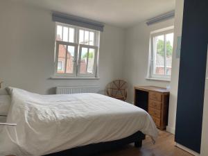 a white bedroom with a bed and two windows at The Farmer's Daughter in Venray