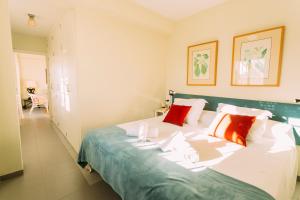 una camera da letto con un grande letto bianco con cuscini rossi di Ático con terraza en el centro de Sevilla a Siviglia