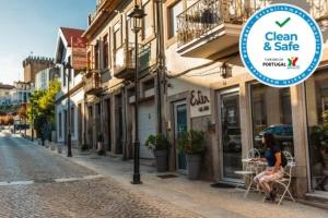 a woman sitting in a chair outside a shop on a street at Ester Guest House in Chaves