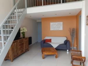 L' Albizia في Pintheville: غرفة معيشة مع أريكة زرقاء وسرير