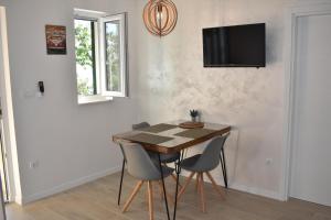 mesa de comedor con sillas y TV en la pared en Guest House Vineyard oaza, en Brela