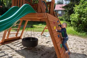 a young child playing on a playground with a slide at Hostel Szczelinka in Pasterka