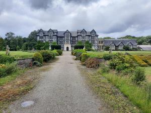 a large black and white mansion with a dirt road at The Rhiw in Newtown