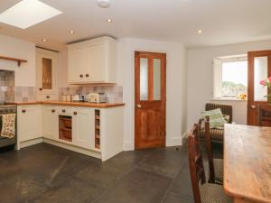 una cucina con armadi bianchi e tavolo in legno di Limers Cottage a Buxton