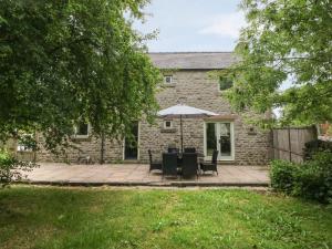 a stone house with a patio with an umbrella at Limers Cottage in Buxton
