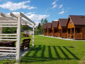 a group of wooden lodges in a grassy yard at Morskie Opowieści in Mikoszewo