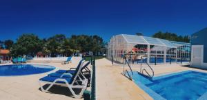 a swimming pool with chairs and a glass house at Camping Villa Park Zambujeira do Mar in Zambujeira do Mar