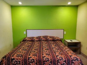 a bedroom with a bed with a green wall at Travel Inn Motel in Hartford
