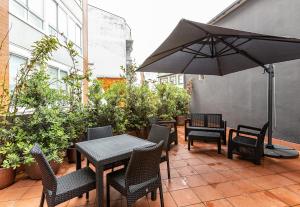 eine Terrasse mit Tischen, Stühlen und einem Sonnenschirm in der Unterkunft Apartamentos Pensua Sisargas in Malpica