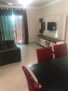 sala de estar con mesa negra y sillas rojas en Apto Piratuba Termas, en Piratuba