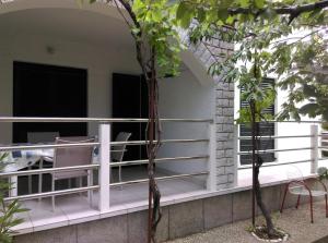 a porch with white railing and chairs and trees at Apartmani Vrzić in Baška