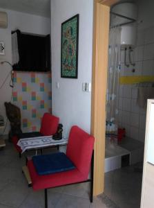 a bathroom with two red chairs and a shower at Apartmani Vrzić in Baška +11 photos