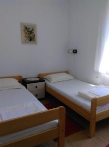 two twin beds in a room with a window at Apartmani Vrzić in Baška