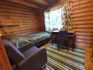a room with a bed and a desk and a chair at Viihtyisä hirsimökki järven rannalla in Siikainen