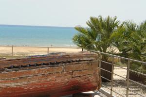 una panchina di legno accanto a una spiaggia con palme di Sapore di Mare a Porto Empedocle