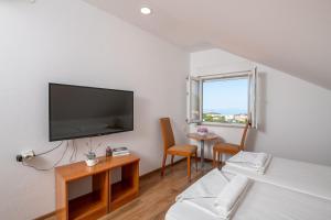 a room with a tv on a wall with a bed at Country House Pansion in Cavtat