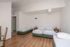3 camas en una habitación con suelo de madera en Country House Pansion, en Cavtat