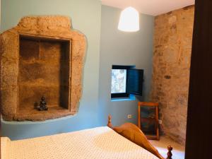 1 dormitorio con cama y pared de piedra en Santiaguiño 2 en Padrón