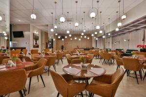 a dining room with tables and chairs and lights at Hotel Fernandópolis in Fernandópolis