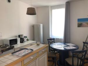 - une cuisine avec une table, un four micro-ondes et une table dans l'établissement Appartement à 2 minutes de la plage 5 places, à Berck-sur-Mer