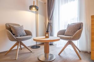 2 sillas y una mesa con una lámpara en una habitación en Hotel Meida, en Pozza di Fassa