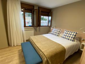 um quarto com uma cama grande e 2 janelas em Hotel Baltico 2 estrellas em Luarca