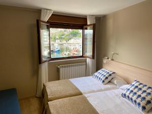 Schlafzimmer mit einem Bett und einem Fenster in der Unterkunft Hotel Baltico 2 estrellas in Luarca