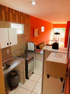 a kitchen with orange walls and a stove top oven at Casa em Gravata mobiliada in Gravatá