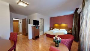 ein Hotelzimmer mit einem Bett und einem Tisch und Stühlen in der Unterkunft Hotel Via Roma in Salzburg