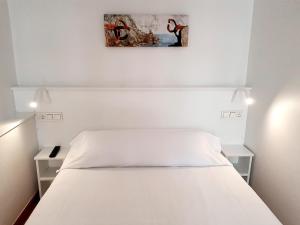 a bedroom with a white bed with two night stands at Pensión Régil in San Sebastián