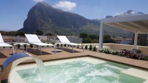 a swimming pool with chairs and a mountain in the background at Artemide Hotel in San Vito lo Capo