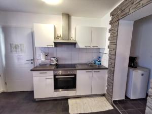 a kitchen with white cabinets and a stove top oven at Apartments Plejic in Seget Vranjica