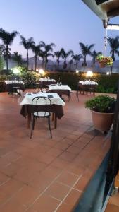 d'une terrasse avec des tables, des chaises et des palmiers. dans l'établissement Agriturismo Il Pozzo Antico, à Mascali