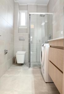 a bathroom with a toilet and a shower and a washing machine at Faidra Apartments in Nea Peramos