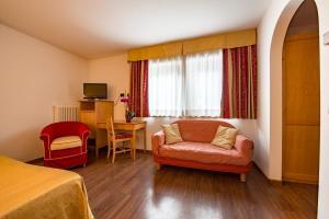 Habitación con cama, silla y ventana en Hotel Alpino Al Cavalletto, en Canazei