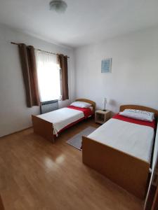 1 dormitorio con 2 camas y ventana en Apartments Plejic, en Seget Vranjica