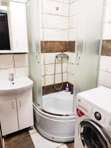 uma casa de banho com um chuveiro e uma máquina de lavar roupa em Дешеві кімнати біля парку em Ivano-Frankivsk