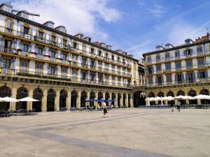 a large building with tables and umbrellas in a courtyard at Pensión Régil in San Sebastián