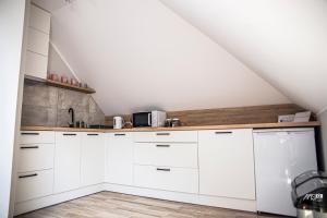 a white kitchen with white cabinets and a staircase at Domek u Mai in Zator
