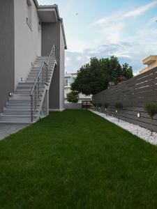 a yard with stairs and green grass next to a building at Faidra Apartments in Néa Péramos